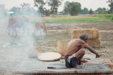 Asyalı yaşlı adam yapma bambu hasır kırsal kesimde.