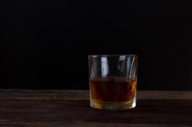 Alkol cam ahşap masa ve siyah arka plan üzerinde buzlu viski viski