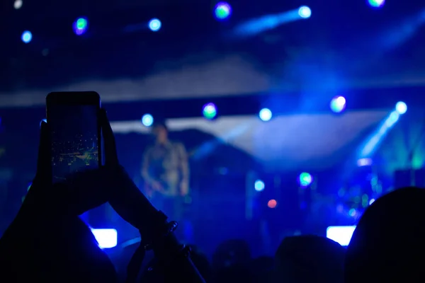 Hand with a smartphone records live music festival, Taking photo of concert stage, live concert, music festival