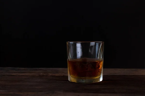 Glas Scotch-Whisky mit Eis auf Holztisch und schwarzem Hintergrund — Stockfoto