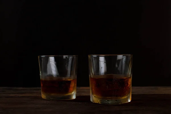 Glas Scotch-Whisky mit Eis auf Holztisch und schwarzem Hintergrund. — Stockfoto