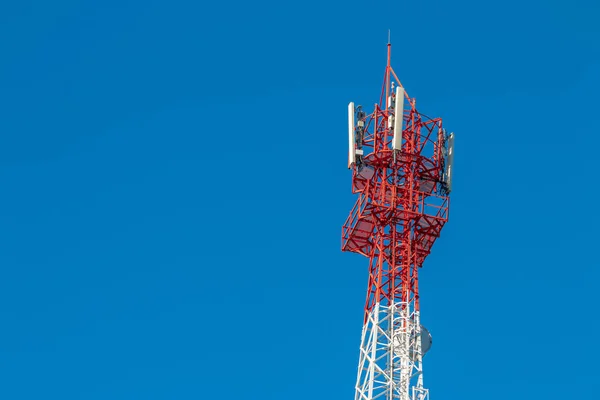 Wireless Communication Antenna Transmitter. Telecommunication tower with antennas on blue sky background.