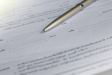 Başka bir kağıt seti ile bir klasörde beyaz kağıt üzerinde yatan altın kalem düşük açı görünümü 
