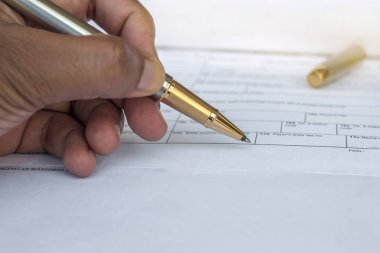 Başka bir kağıt seti ile bir klasörde beyaz kağıt üzerinde yatan altın kalem düşük açı görünümü 