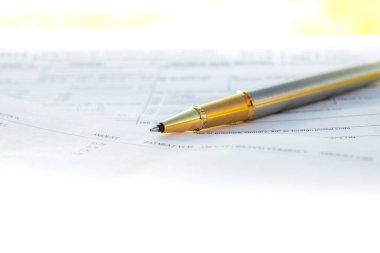 Başka bir kağıt seti ile bir klasörde beyaz kağıt üzerinde yatan altın kalem düşük açı görünümü 
