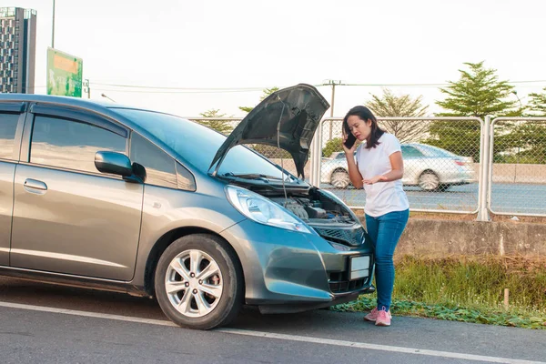 Broken car on side of the road with woman calling for help, Woman calling for help by phone.