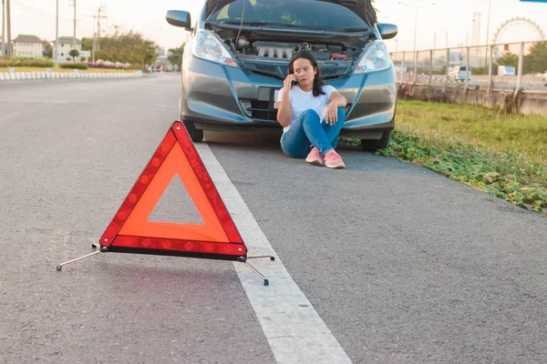 Broken car on side of the road with woman calling for help, Woman calling for help by phone.