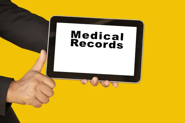 Medical record system show on tablet in someone hand on yellow background.