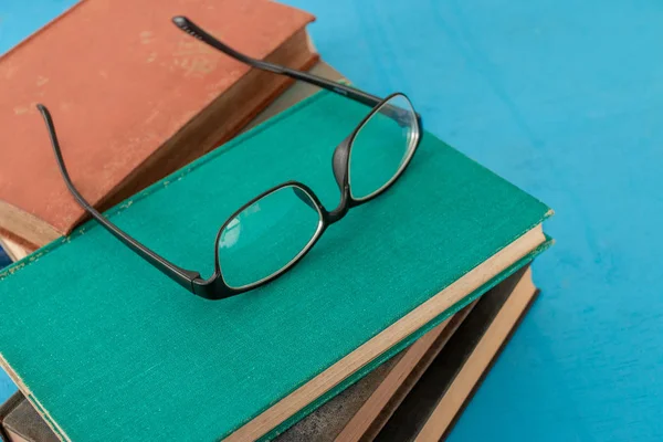 Alte Bücher Und Schwarze Brillen Auf Blaugrünem Holz — Stockfoto