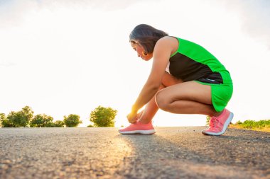Yol boyunca yamaç bölgesinde güneş battığı sırada kadın koşarak egzersiz.