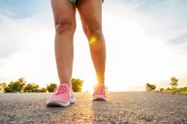 Yol boyunca yamaç bölgesinde güneş battığı sırada kadın koşarak egzersiz.