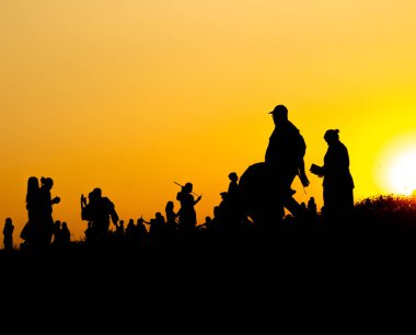 Birçok turist siluet gün batımı saatlerinde dağın tepesinde akıllı telefon ile fotoğraf çekiyor.