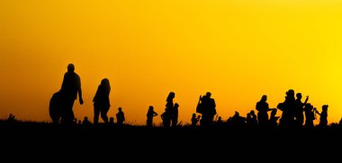 Birçok turist siluet gün batımı saatlerinde dağın tepesinde akıllı telefon ile fotoğraf çekiyor.