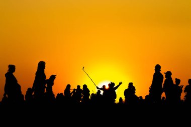 Birçok turist siluet gün batımı saatlerinde dağın tepesinde akıllı telefon ile fotoğraf çekiyor.