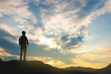 gökyüzü ve güneş ışığı arka plan üzerinde dağ üstünde backpacker silueti, iş, başarı, liderlik, başarı ve insan kavramı