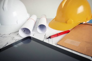 Tasarım ofisindeki mimarın ofisinde bir plan, güvenlik şapkası ve mimar aletleri var..