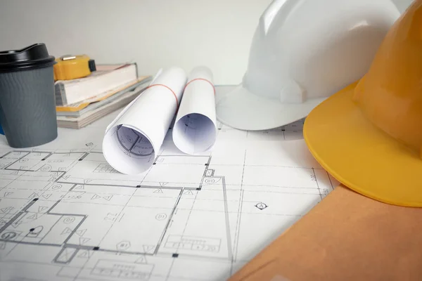 Tasarım ofisindeki mimarın ofisinde bir plan, güvenlik şapkası ve mimar aletleri var..