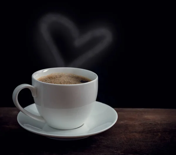 Cup of coffee with heart shape smoke on old wooden table