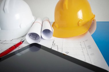 Tasarım ofisindeki mimarın ofisinde bir plan, güvenlik şapkası ve mimar aletleri var..