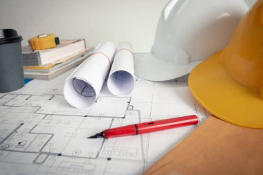 Tasarım ofisindeki mimarın ofisinde bir plan, güvenlik şapkası ve mimar aletleri var..
