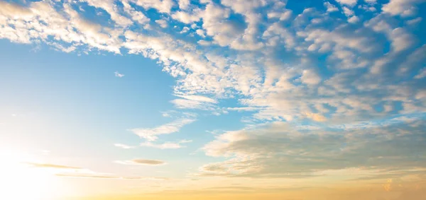 Mavi gökyüzü arka planda. Bulutları ve gökyüzünde turuncu güneşi olan güzel bir manzara.