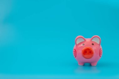 Pastel mavi arka planda pembe kumbara, finansal kavramlar