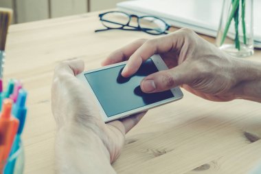 İşadamı ekran yatay smartphone ya da hareket eden telefon içinde vintage yakından uzaklaştırmak yakınlaştırın. Akıllı telefon veya cep telefonu ve kalem ve gözlük ve laptop ya da defter ev ofis ahşap tablo