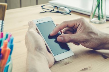 İşadamı ekran yatay smartphone ya da hareket eden telefon içinde vintage yakından uzaklaştırmak yakınlaştırın. Akıllı telefon veya cep telefonu ve kalem ve gözlük ve laptop ya da defter ev ofis ahşap tablo
