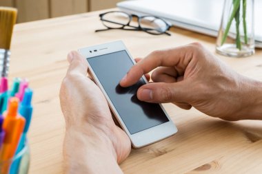 İşadamı yakınlaştırma yakınlaştırma ekran yatay akıllı telefon veya cep telefonu yakın dışarı kadar. Akıllı telefon veya cep telefonu ve kalem ve gözlük ve laptop ya da defter ev ofis ahşap tablo