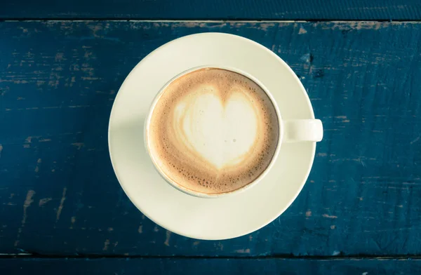 Vintage hart vorm froth melk Latte kunst in witte koffie kopje op zwarte houten tafel — Stockfoto