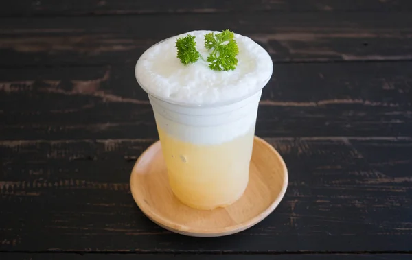 Suco de abacaxi com espuma de leite e salsa no centro de mesa de madeira preta — Fotografia de Stock