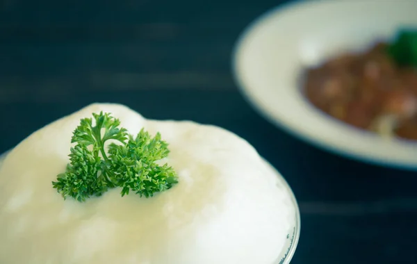 Milchschaum und Petersilie auf schwarzem Holztisch — Stockfoto