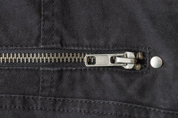 Gesloten messing ritssluiting op zwarte jeans textuur achtergrond close-up weergeven — Stockfoto