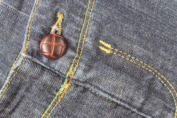 Kruis jeans textuur achtergrond en bruine knop Crosswise View — Stockfoto