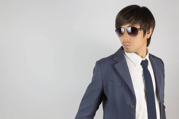 Молодой азиатский портретист-бизнесмен в синем костюме носит солнцезащитные очки — стоковое фото