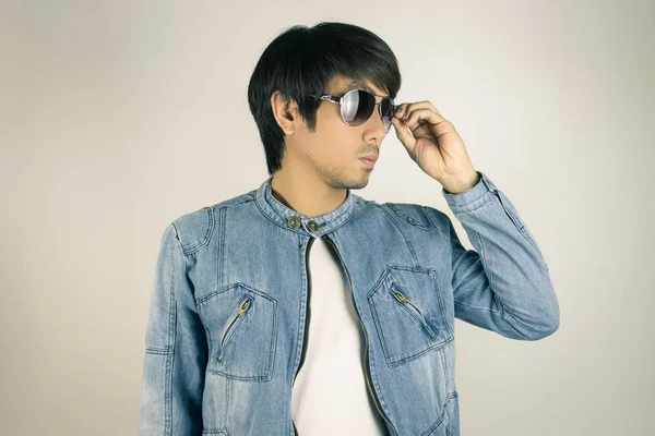 Молодой азиат в джинсах или джинсовой куртке коснулся солнцезащитных очков — стоковое фото