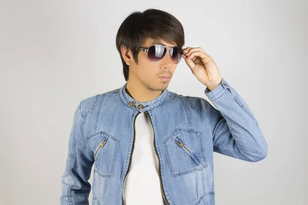 Молодой азиат в джинсах или джинсовой куртке касаясь солнцезащитных очков — стоковое фото