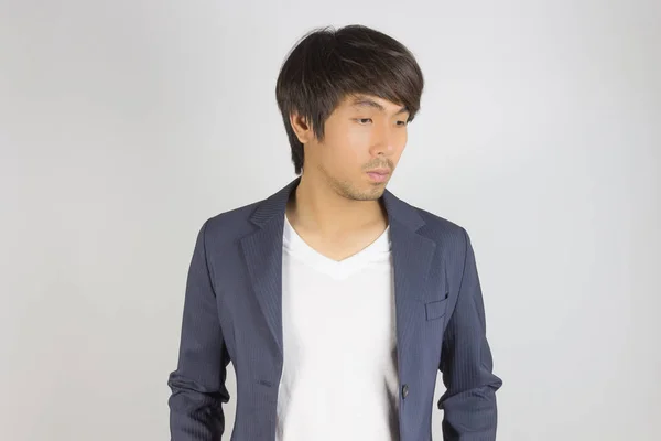 Πορτρέτο Ασίας Casual Επιχειρηματίας στο κοστούμι εξετάσουμε παρακάτω σε γκρι φόντο — Φωτογραφία Αρχείου