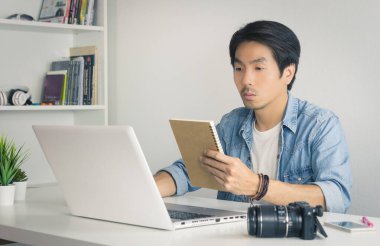 Asyalı Fotoğrafçı veya Freelancer Çalışma Çizelgesini Klasik Tondaki Not Defterinde Denetliyor