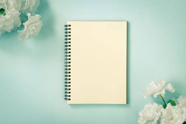 Spiral Notebook veya Spring Notebook in Unline Type and White Flowers at Top Left Corner and Bottom Right Corner on Blue Pastel Minimalist Arkaplan