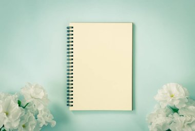 Spiral Notebook ya da Spring Notebook in Unline Type and White Flowers at Bottom on Blue Pastel Minimalist Arka plan in Vintage Tone