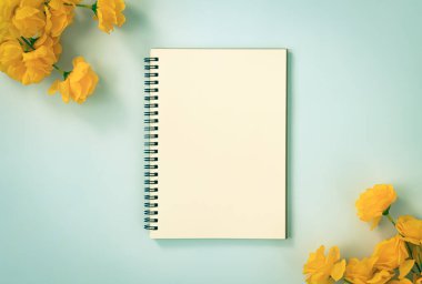 Spiral Notebook veya Spring Notebook in Unline Type and Orange Flowers at Bottom Right and Top Left Corner on Blue Pastel Minimalist Background. Vintage Tondaki Orta Çerçevede Spiral Not Defteri Model