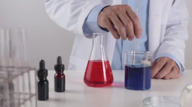 Laboratuvar önlüklü genç bilim adamı deney ve araştırma için mavi çözeltiyi karıştırdı. Corona Virüs Hastalığı Laboratuvarında Çalışan Bilim Adamı veya Covid 19 Durumu