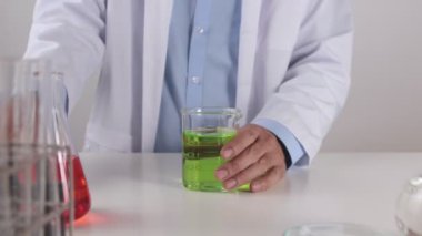 Laboratuvar önlüklü genç bilim adamı test için deney kabında yeşil çözeltiyi karıştırdı. Corona Virüs Hastalığı Laboratuvarında Çalışan Bilim Adamı veya Covid 19 Durumu