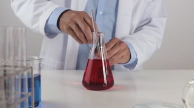 Erlenmeyer Matarası 'ndaki Laboratuvar Önlüğü Bırakma Çözümü' nde genç bir bilim adamı. Corona Virüs Hastalığı Laboratuvarında Çalışan Bilim Adamı veya Covid 19 Durumu