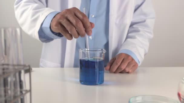 Jovem Cientista Lab Coat Stir Solução Azul Beaker Homem Cientista — Vídeo de Stock