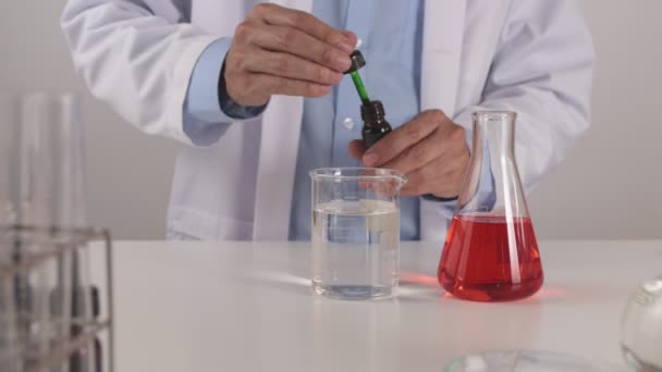 Young Scientist Man Lab Coat Drop Roer Green Solution Beaker — Stockvideo