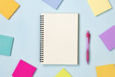 Spiral Notebook veya Spring Notebook in Unline Type and Multi Color Sticky Note and Pink Pen on Blue Pastel Minimalist Arkaplan. Orta Çerçevede Spiral Not Defteri Model