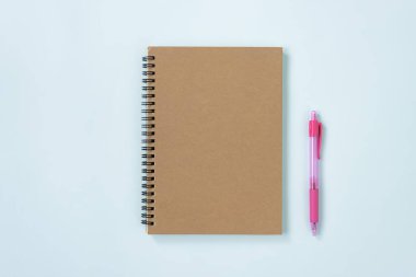 Brown cover Spiral Notebook ya da Unline Type ve Pink Pen on Blue Pastel Minimalist Arkaplan. Orta Çerçevede Spiral Not Defteri Model