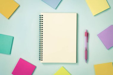 Spiral Notebook veya Spring Notebook in Unline Type and Multi Color Sticky Note and Pink Pen on Blue Pastel Minimalist Arkaplan. Vintage Tondaki Orta Çerçevede Spiral Not Defteri Model